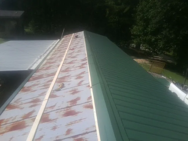 Old rusted panels beside newly installed green metal roofing — Wind Damage Roof Repair by Roofing Brothers in Thornwood