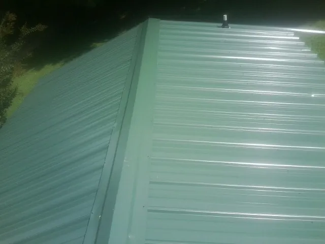 New green metal panels meeting at the ridge of a roof — Flat Roof Repair work by our crew in Thornwood