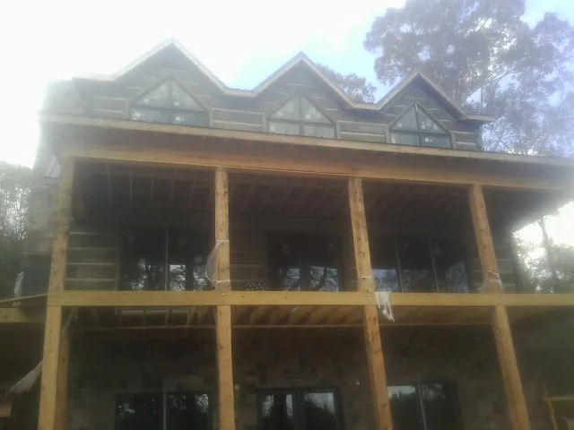 Dormers and porch framing on a large log home under construction — Roof Coating work by our crew in Thornwood