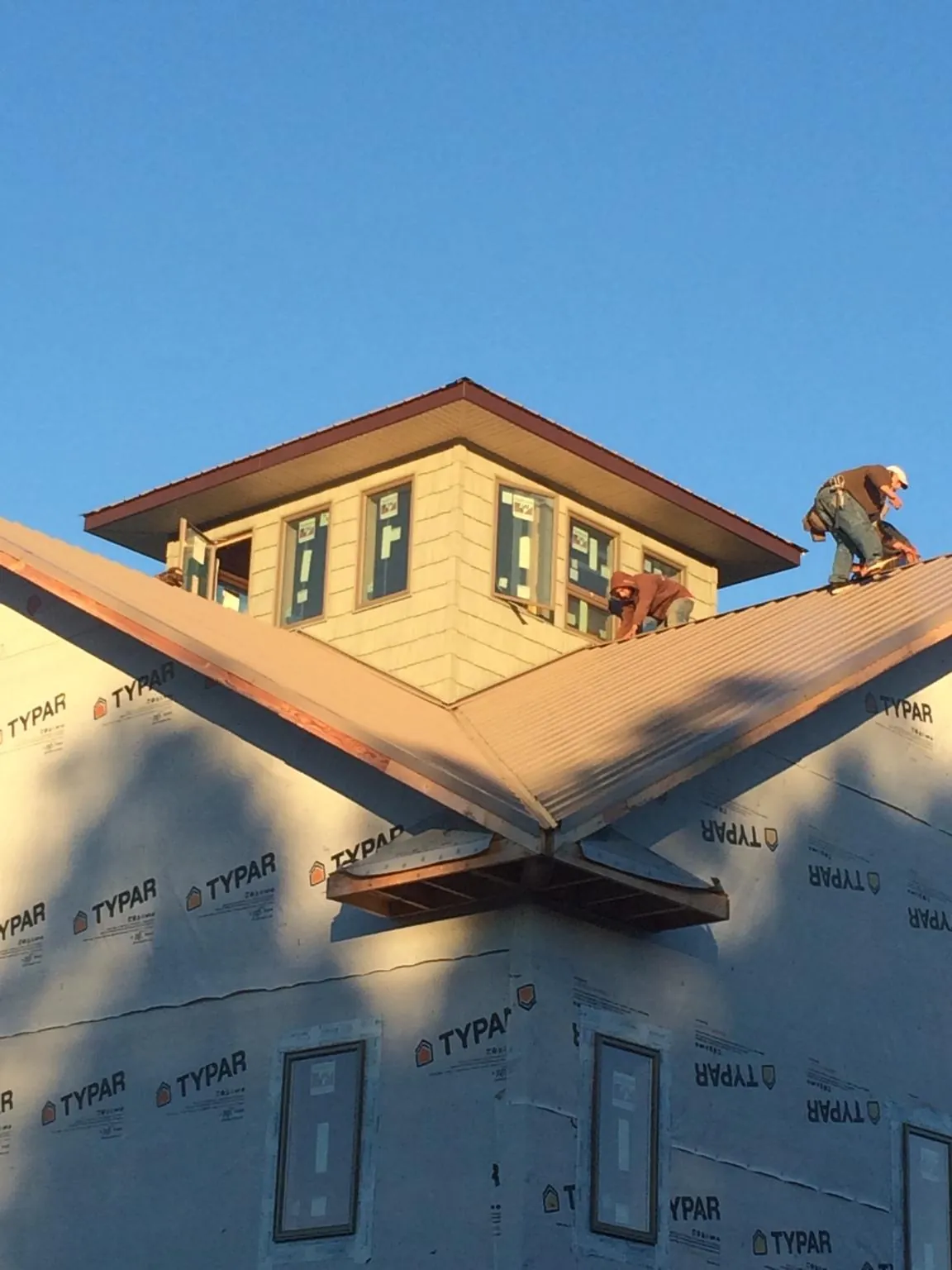 Roofers working around a rooftop cupola on a new metal roof at sunset — Roof Waterproofing in Thornwood by Roofing Brothers